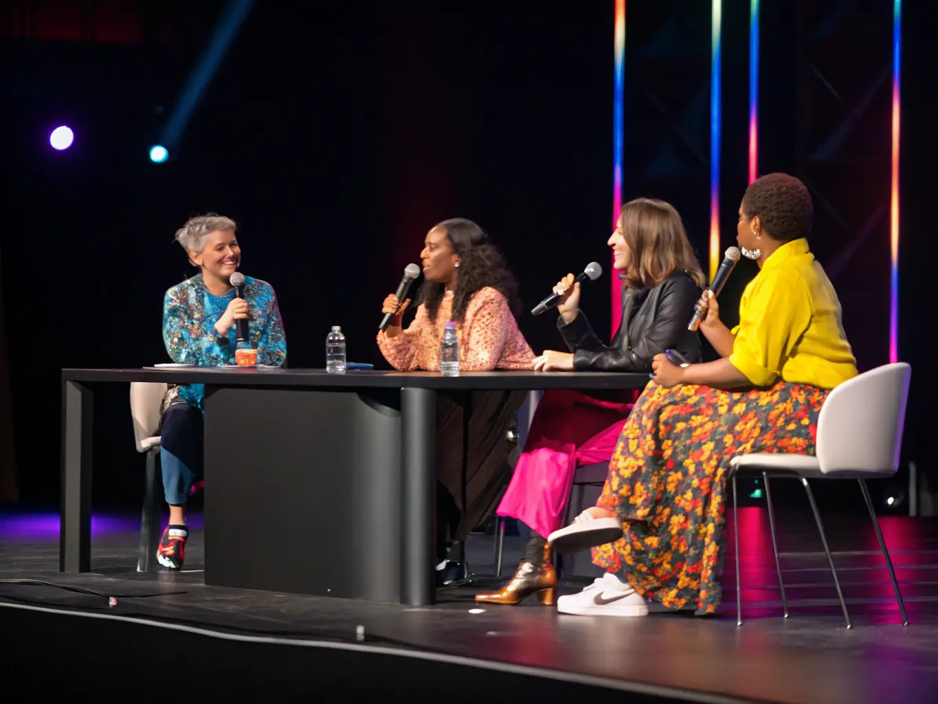 A photograph capturing a lecture or panel discussion featuring fashion experts and historians, with an engaged audience participating in the event.